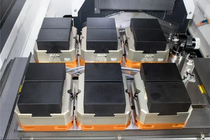six Air Vise AV-T-6 table vises mounted on a machine bed