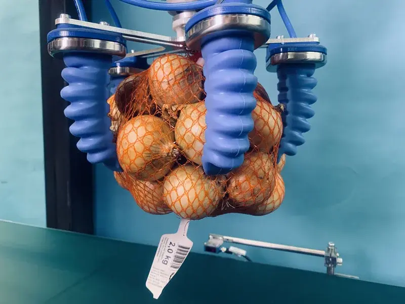 SoftGripping Centric Gorilla Finger Actuator gripping a net bag of onions, shown from the side