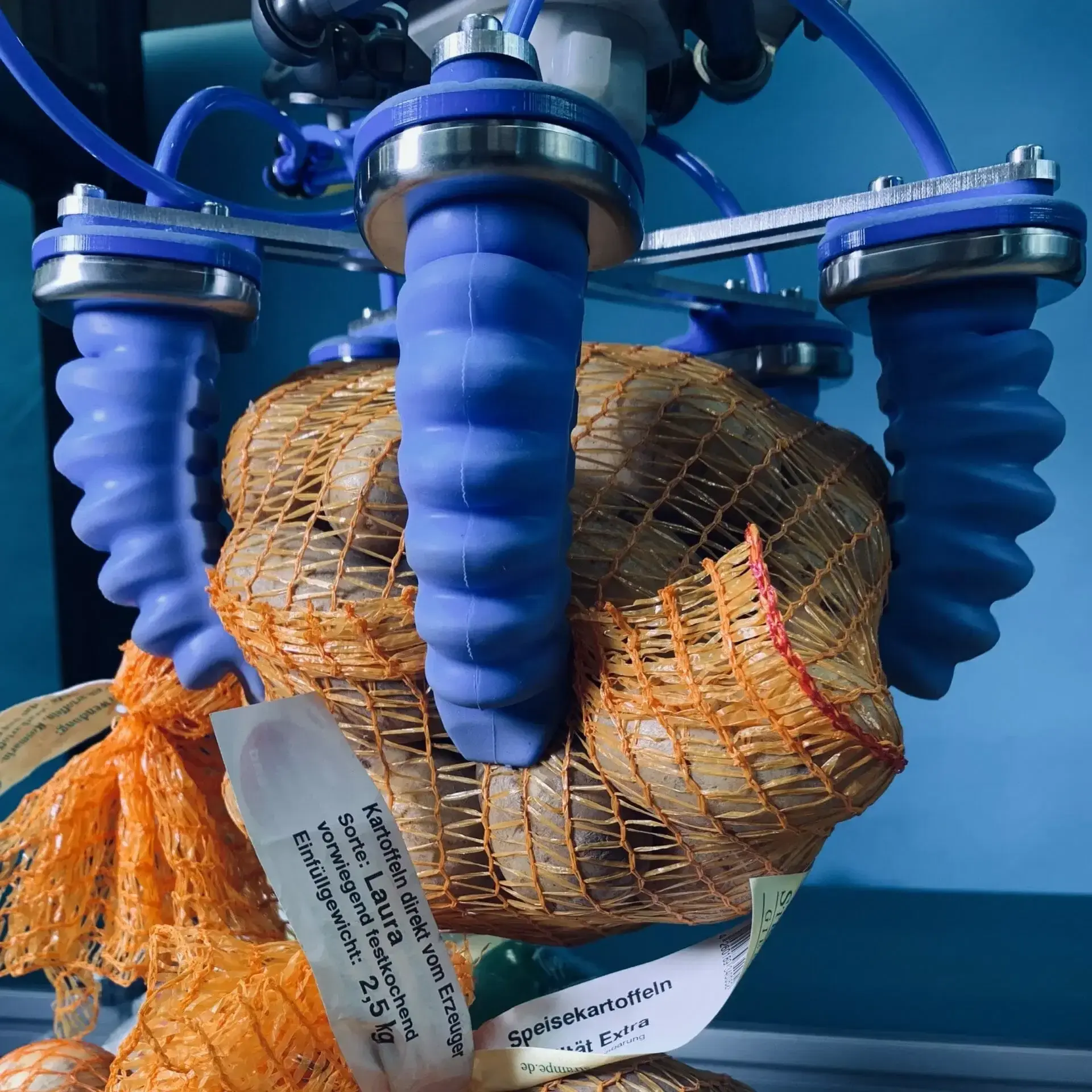 close-up of a soft gripper with four fingers holding a netted bag