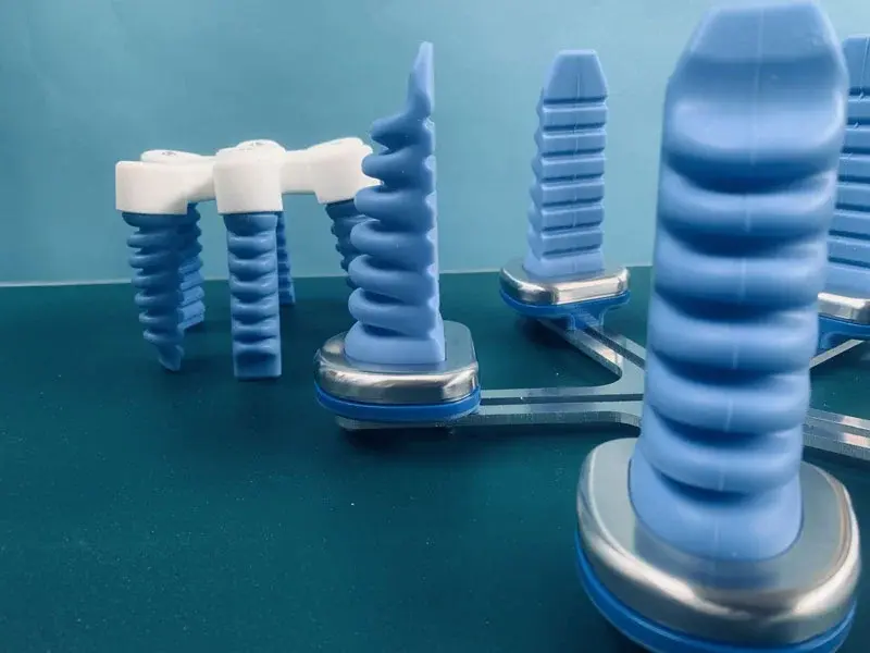 close-up side view of blue soft gripping actuator fingers on a metal frame against a teal background