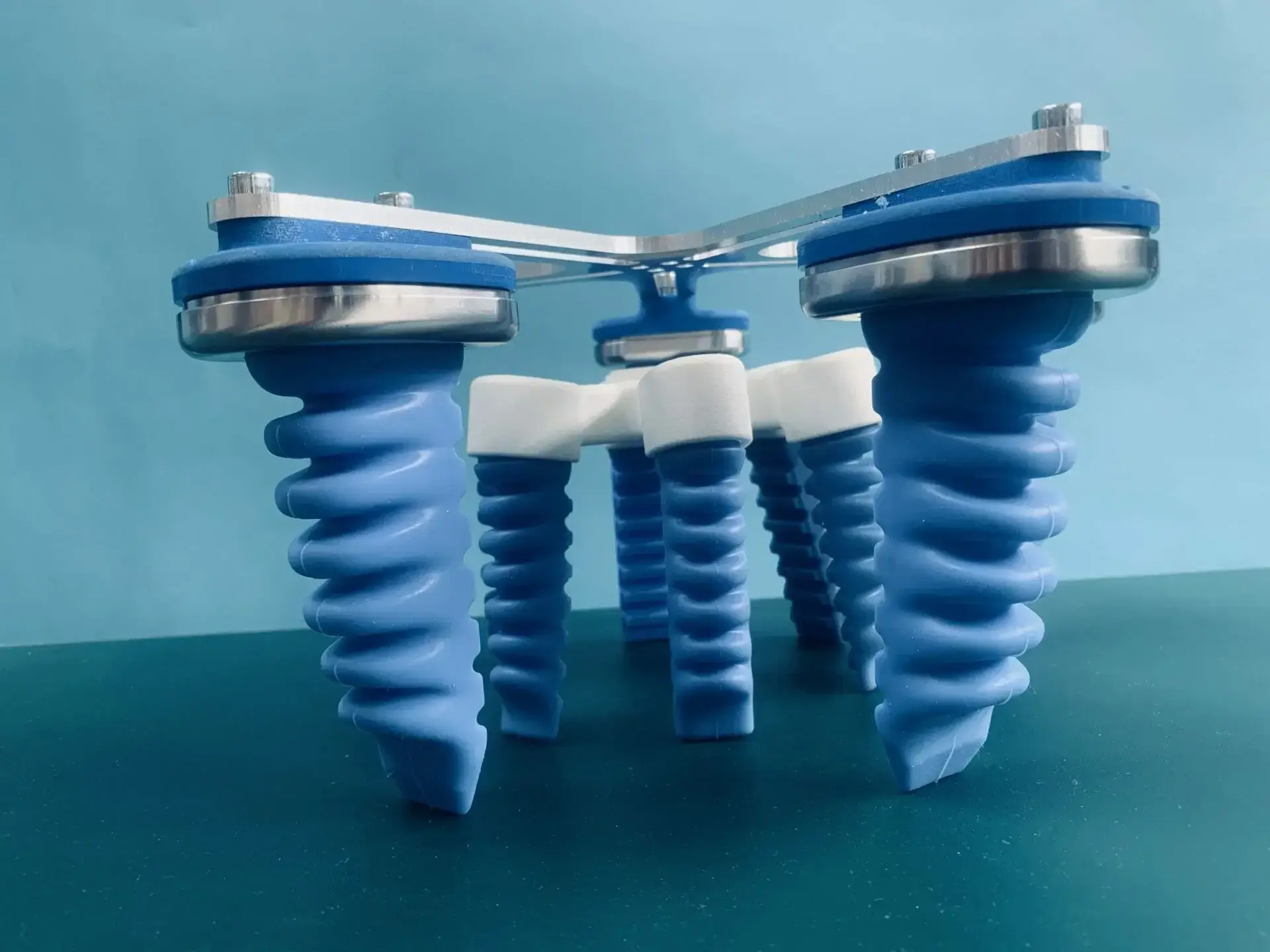 close-up low-angle view of blue soft gripper fingers mounted on metal arms against a blue background