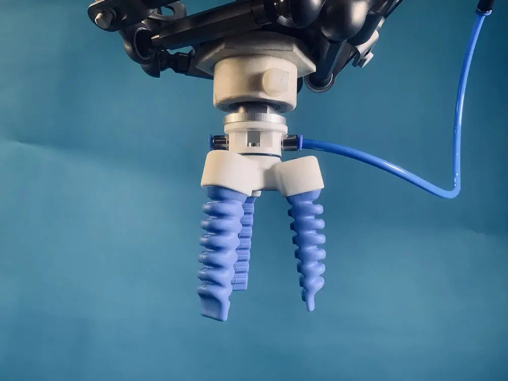 front view of a two-finger centric gripper with blue flexible fingers attached to a robotic arm