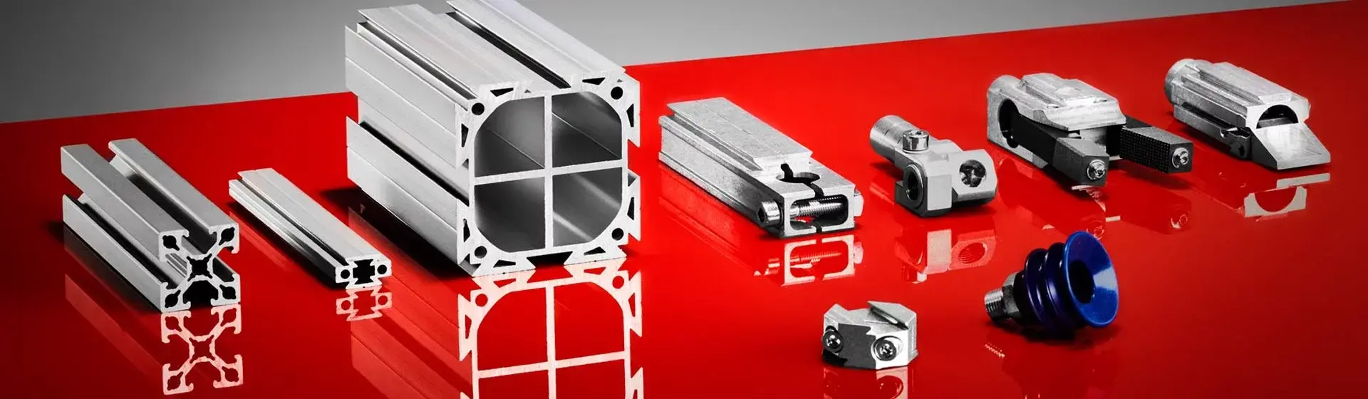 Front view of metal profile and gripper components on a red surface