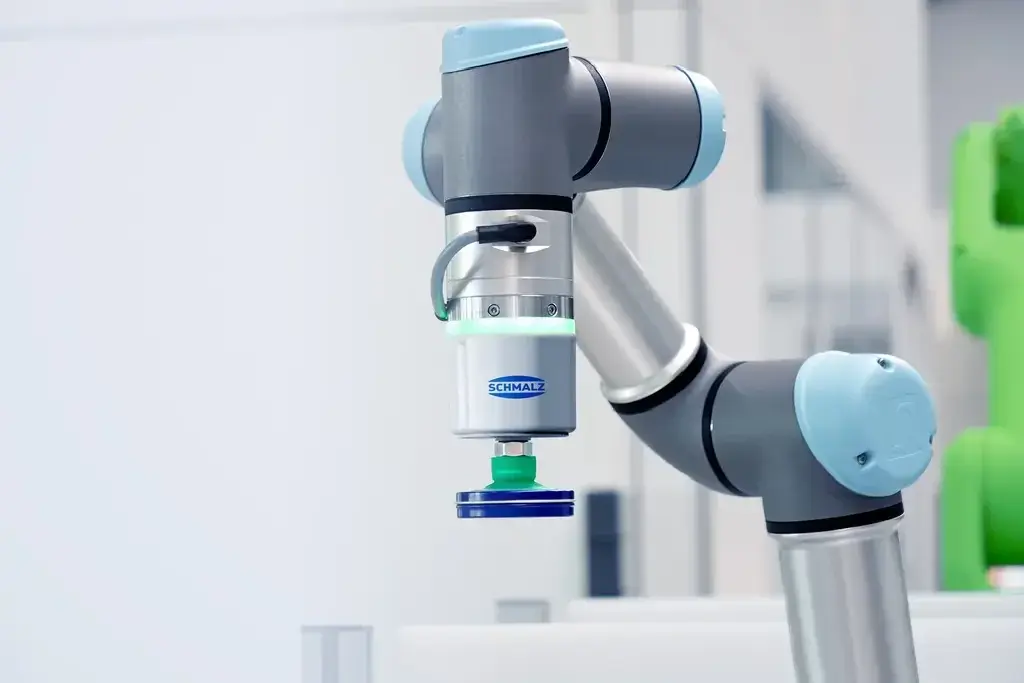 Schmalz CobotPump mounted on a robotic arm with a green suction cup attached