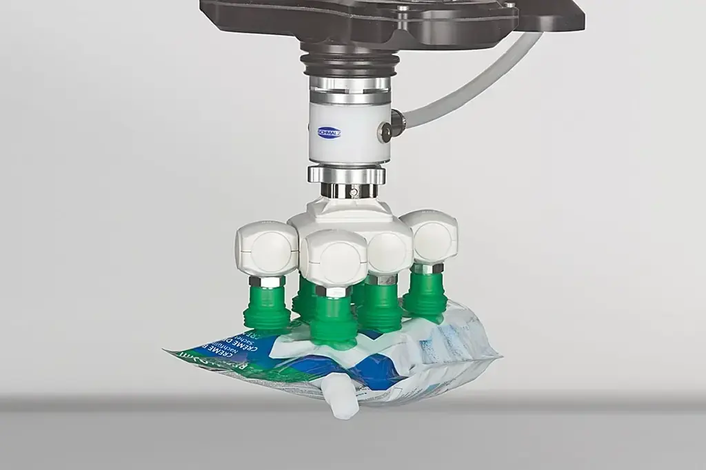 Vacuum gripper with six green cups holding a soft package from the bottom
