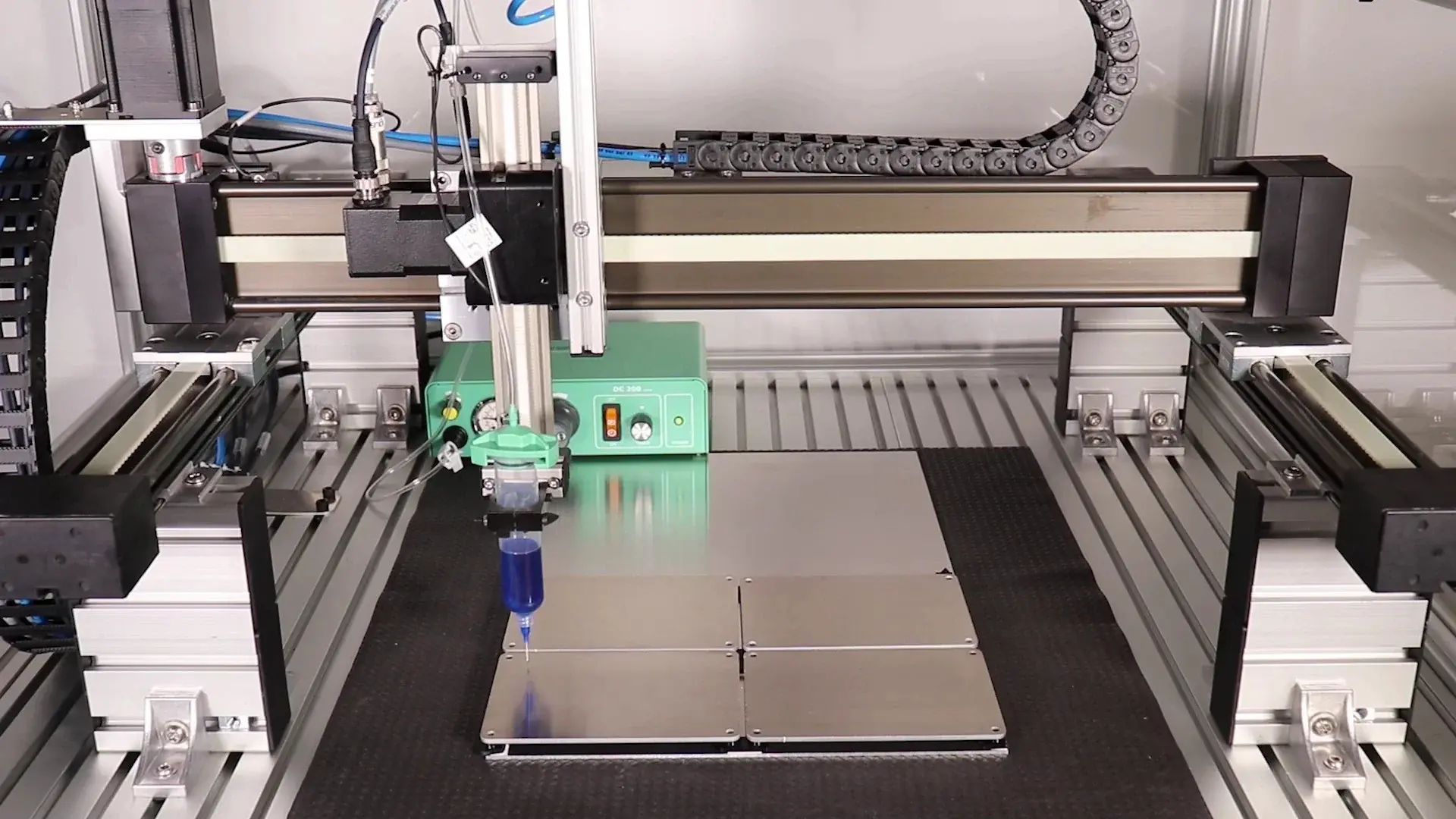 Cartesian gantry robot applying blue fluid on four metal plates