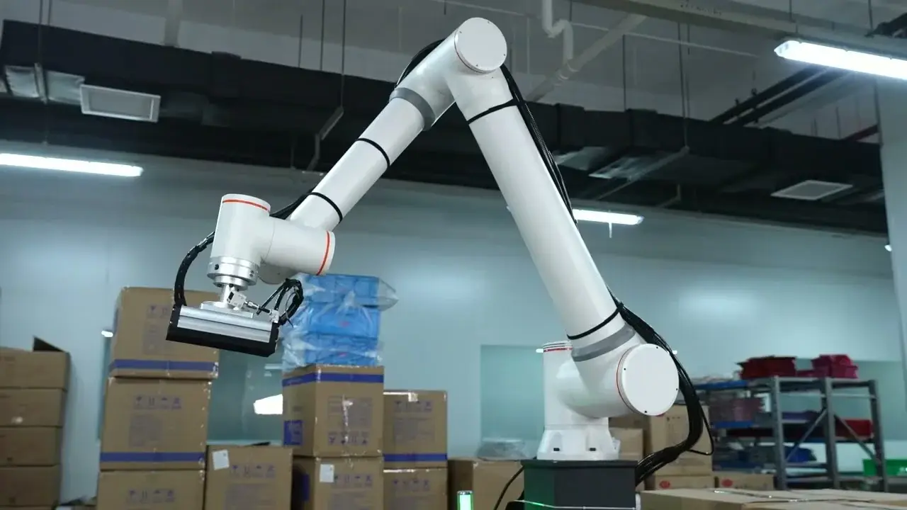 cobot arm operating in a warehouse setting with cardboard boxes in the background